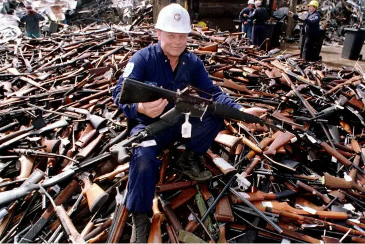 A police officer sits atop a mountain of guns