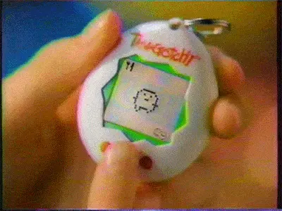 A human hand interacting with a Tamagotchi