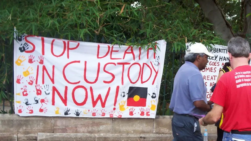 A protest flag with Aboriginal symbols and a message, “Stop death in custody now!